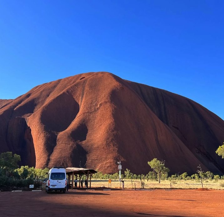 A tour coach parked below Uluru at the viewing area