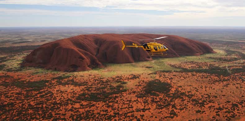 An aerial view of Uluru with the desert plain running out behind it