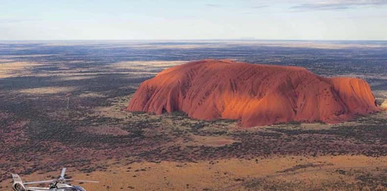 Uluru seen whole from the air, its gullies shadowed along the flank